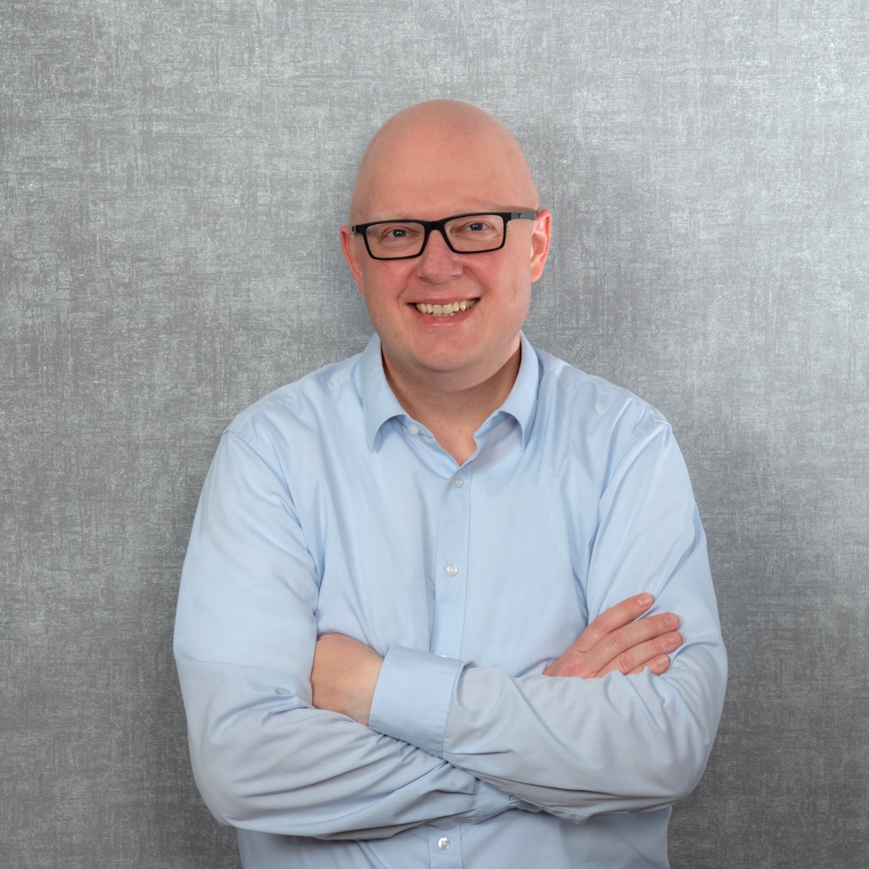 Thorsten Jungmann, ein Mann mit kurzen, blonden Haaren, dunkler Brille und hellblauem Hemd